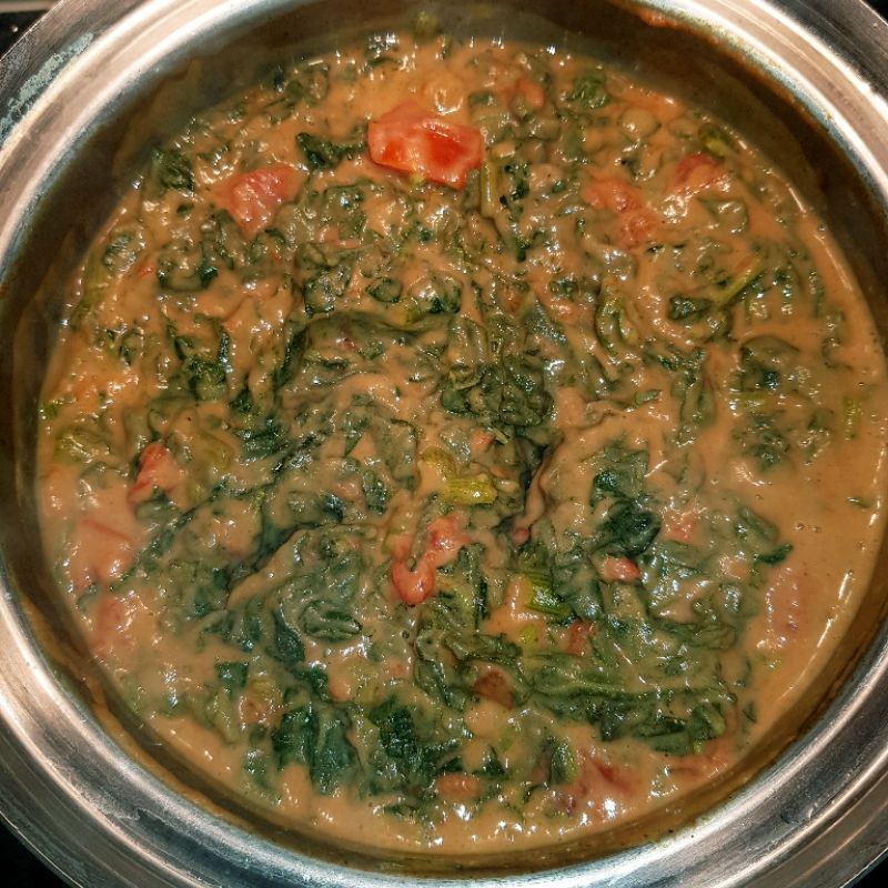 Pumpkin leaves cooked in peanut butter is seen in a clay pot at a